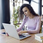 young-woman-working-on-laptop-in-coffee-shop-K9HY7LD-1.jpg